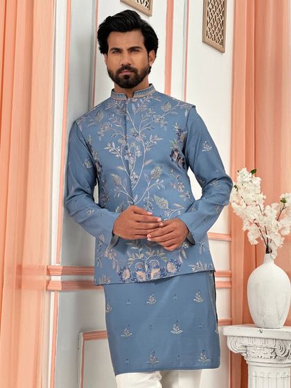 A sophisticated choice for a Sangeet or engagement. This dusty blue kurta set is elevated by a matching jacket featuring delicate floral embroidery, offering a subtle yet impactful statement.