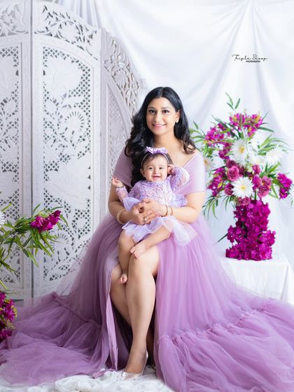 A stunning mother-daughter portrait. The matching lavender gowns and beautiful floral props create a dreamy, fairytale-like image.