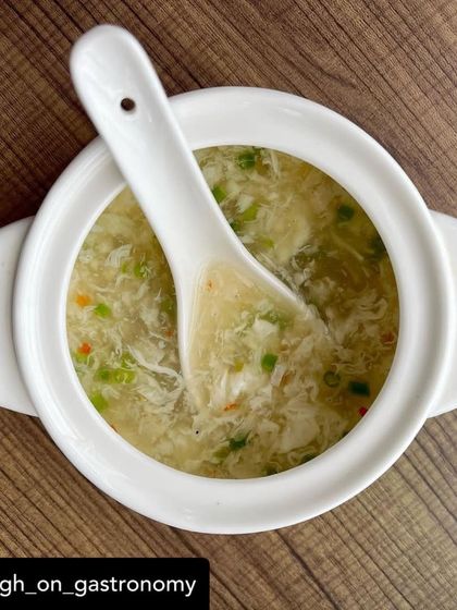 A comforting bowl of our Crab and Asparagus Soup. This top-down shot shows the rich texture of the soup, with delicate crab meat, fresh asparagus, and egg drop, making it a perfect starter for your meal.