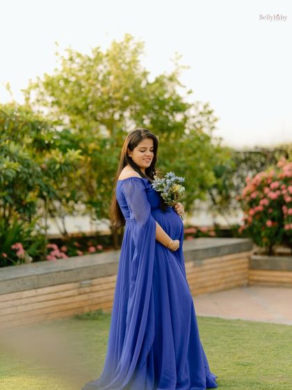 A vision in royal blue. This elegant gown with cape-like sleeves adds a touch of drama and grace to this outdoor solo maternity portrait.