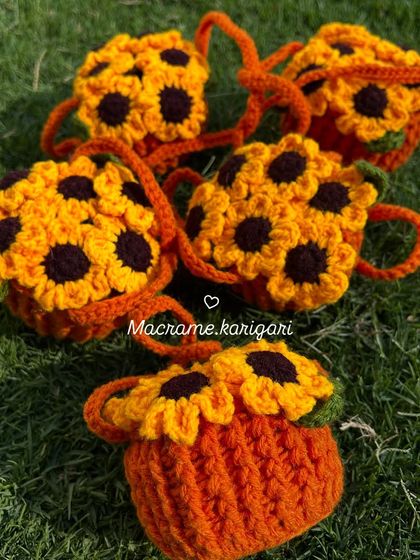 Our adorable sunflower pot car charms, laid out on the grass. These mini hanging pots are perfect for adding a touch of handmade nature to your car.