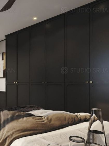 A bedroom in Varanasi with bold, black, floor-to-ceiling wardrobes that feature classic paneling, creating a dramatic and sophisticated look.