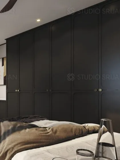 A bedroom in Varanasi with bold, black, floor-to-ceiling wardrobes that feature classic paneling, creating a dramatic and sophisticated look.