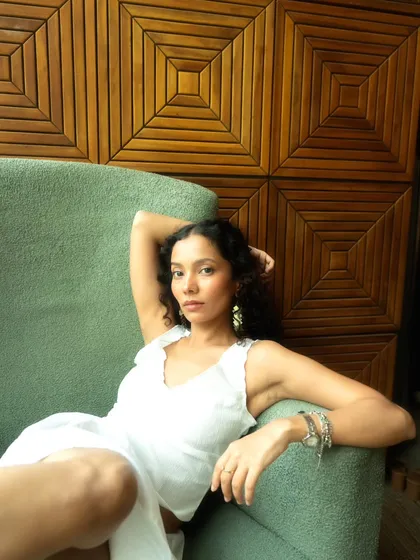A relaxed and confident portrait in an armchair. The wooden paneling in the background adds warmth and texture.