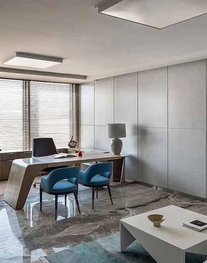 This director's cabin at the Stainless Steel Office uses a cool color palette with grey marble floors and textured wall panels. The design creates a calm and sophisticated atmosphere, reflecting the ethos of its user.