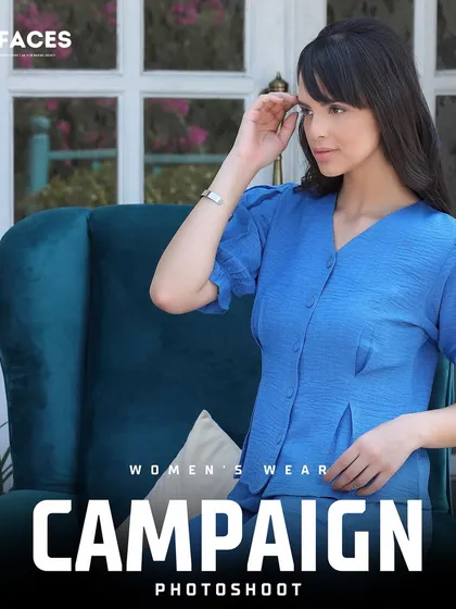 A model in a blue printed top poses in an elegant armchair. The composition and setting create a sophisticated lifestyle image, perfect for a high-end women's wear campaign.