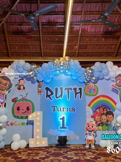 A Cocomelon first birthday party under a gazebo. This setup features a full character backdrop, light-up number '1', and balloon columns in blue, white, and silver.