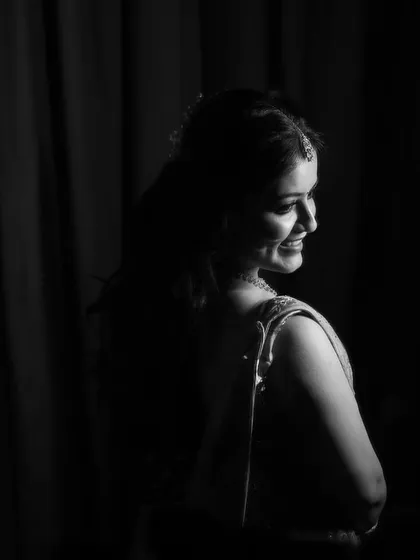 A classic black and white portrait of the bride looking over her shoulder with a gentle smile. The dramatic lighting creates a timeless and elegant image that highlights her happiness.