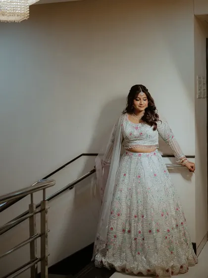 A full-length shot of the bride on a staircase, showing off her elegant engagement lehenga.