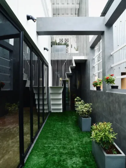 A different angle of the green corridor, showing the external staircase and the interplay of solid and void in the building's facade, all unified by the strip of green.