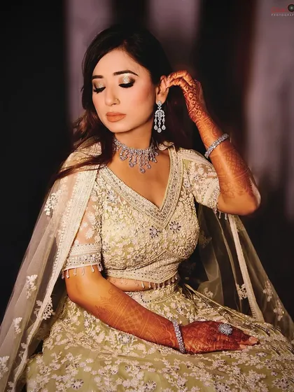 A candid-style portrait of a woman in an elegant, embroidered lehenga. This shot captures a quiet, graceful moment, highlighting the intricate jewelry and soft makeup, perfect for a pre-wedding or engagement session.