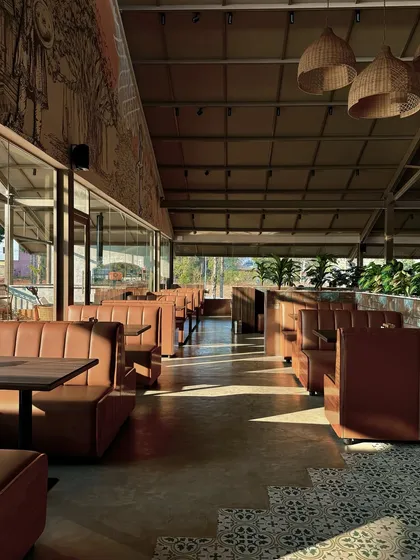 Natural light was a key element in our design for this Devanahalli restaurant. We used floor-to-ceiling glass walls to connect the dining space with the outdoors, while the morning sun highlights the textures of the leather booths, wooden tables, and patterned floor tiles.
