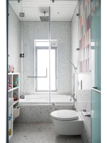 A full view of the baby's bathroom, showing the bright, light-filled space with its terrazzo-style finish and a combination tub and shower.