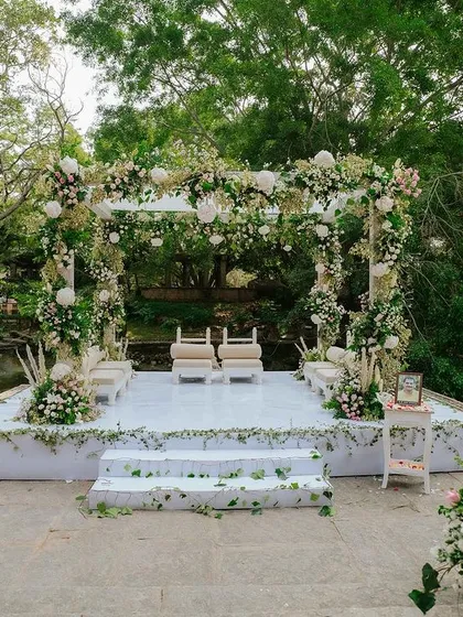 A pristine white mandap at the Pond Pavilion, decorated with lush greenery and white florals for a fresh, organic wedding theme.