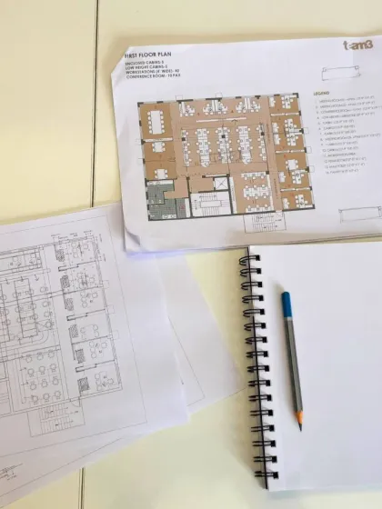 An architect's desk tells a story of the design process. Here, printed floor plans sit alongside a blank sketchbook, ready for the next idea or refinement.