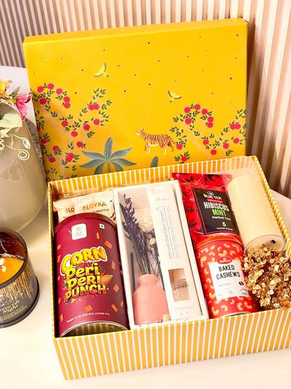 Our Festive Delight hamper lives up to its name with a bright, cheerful yellow box. It's packed with a variety of snacks like peri-peri corn and baked cashews, along with a reed diffuser and an electric candle for a modern festive touch.