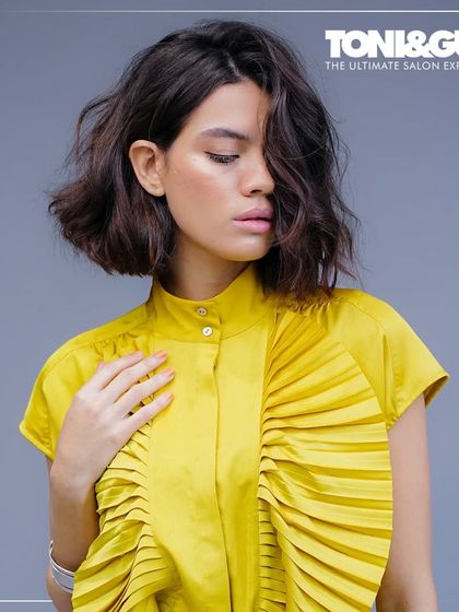 A forward graduation bob with soft, textured waves. This cut is elevated to accentuate the cheekbones, with artful layering that creates dimensional brilliance and fluid movement, a hallmark of modern elegance.