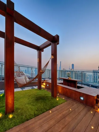 We design urban sanctuaries that offer an escape from the city bustle. This rooftop terrace project combines natural grass, warm wood, and ambient lighting to create a perfect relaxation spot, complete with a hammock overlooking the skyline.