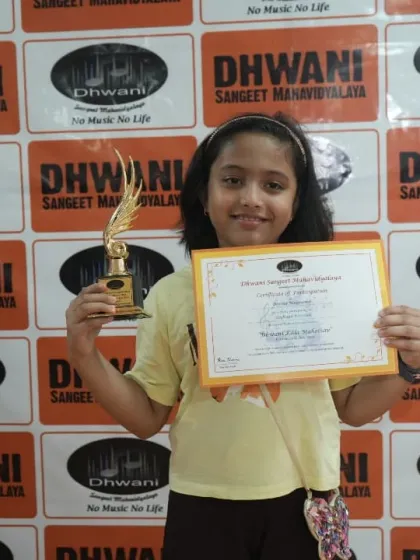 A young student proudly holds her certificate and trophy from the art competition.