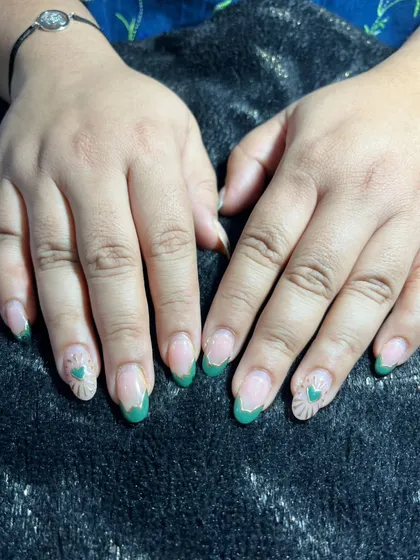 A subtle and sweet design featuring green French tips and accent nails with a textured heart pattern. It's a lovely way to add a touch of art to your nails.