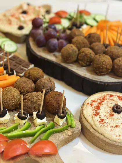 This party spread is all about fresh flavors and beautiful presentation. I've arranged falafel bites with toothpicks, feta and olive skewers, and bowls of creamy hummus, ready for guests to enjoy.