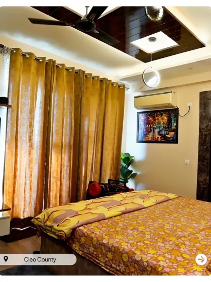 A warm and cozy bedroom with a glossy false ceiling panel and rich golden curtains. This design creates a comfortable and inviting retreat.