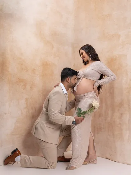 A beautiful, chivalrous moment. The father-to-be kneels to kiss the baby bump, creating a timeless and romantic portrait.