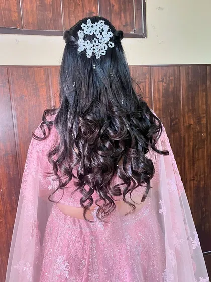 A stunning open hairstyle for an engagement. The hair is styled in voluminous, bouncy curls and adorned with a beautiful crystal accessory.
