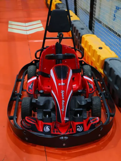 A close-up of our sleek red go-kart, waiting for its next driver. These electric karts are easy to operate and provide a safe, controlled racing experience for children.