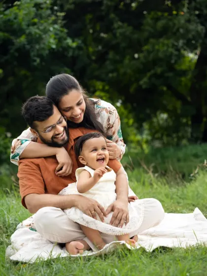 A family shares a heartfelt laugh during an outdoor session in a lush green park. Capturing these unposed, joyful moments is what makes outdoor family photoshoots in Mumbai so special.