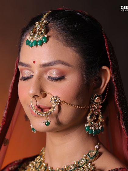 Student Work: A classic bridal makeup look with soft, closed eyes to showcase the detailed eyeshadow work. The green jewelry provides a beautiful contrast to the warm tones.
