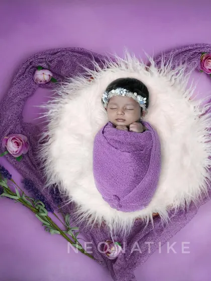A perfect little bundle of love, wrapped in lavender and nestled in a heart-shaped fur basket. This overhead shot is a beautiful way to capture your newborn.