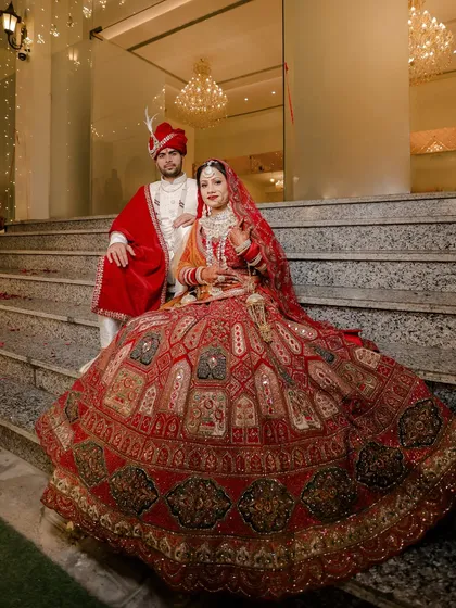 We create grand, magazine-worthy portraits that make you feel like royalty. This shot of Rohit and Neha on the stairs showcases the bride's stunning lehenga and the couple's elegant presence, a classic wedding photograph.