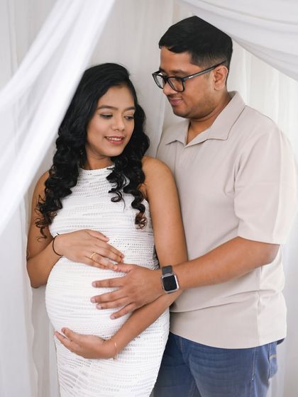 A sweet, interactive moment between the couple. His hand on her belly and their shared gaze make this a heartwarming capture in our bright studio.