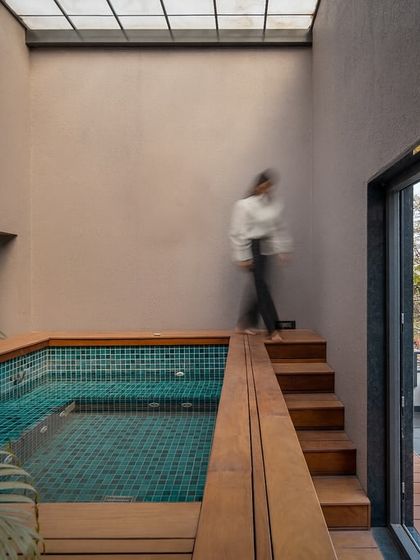 A view of the indoor plunge pool, with a person walking along the wooden steps. This space perfectly captures the villa's blend of luxury, tranquility, and seamless connection to the outdoors.
