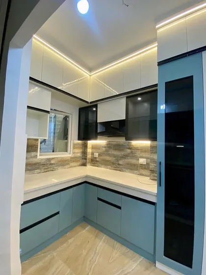 A wide-angle shot of a beautiful blue and white kitchen with a tall glass pantry unit, seen from the entrance.