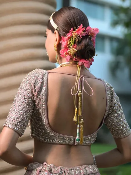 This romantic updo features a low bun intricately decorated with fresh pink flowers. It's a soft yet sophisticated hairstyle perfect for bridal editorials or spring and summer fashion campaigns.