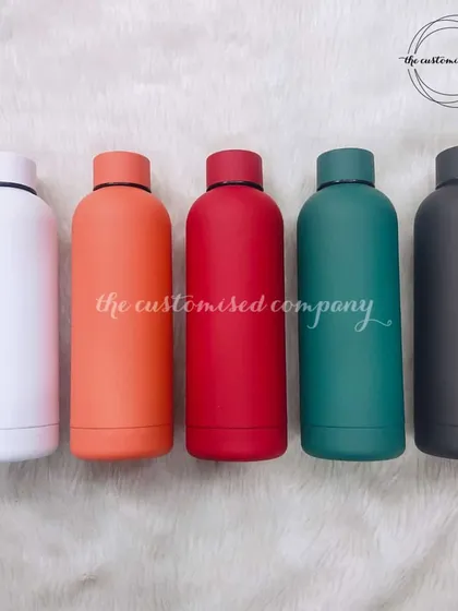 A showcase of the vibrant colors available for our 500ml insulated bottles. Choose from white, orange, red, green, or black to match your style. They keep drinks hot or cold for over 12 hours.