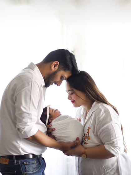 This pose, with the parents' heads touching as they gaze at their baby, creates a beautiful sense of intimacy and shared love. It’s a perfect portrait of a family in their own little world.