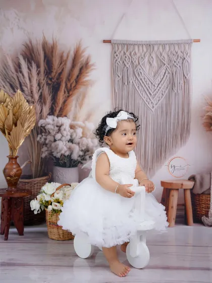 Riding into her second year in style. The white tricycle is a popular prop that adds a playful element to first birthday portraits.
