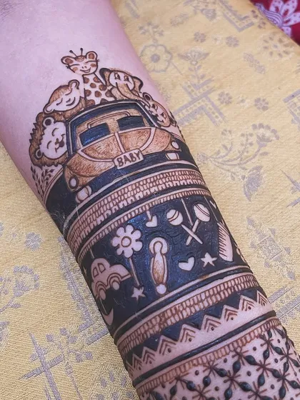 A close-up of a cute baby shower mehendi. This arm band features tiny toys, rattles, and a car full of happy animals, celebrating the little one on the way.
