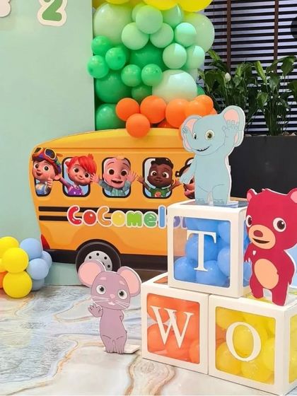 Detail shot from a Cocomelon party showing custom elements like the yellow school bus cutout and 'TWO' letter blocks. These small touches add depth and fun to the overall theme.