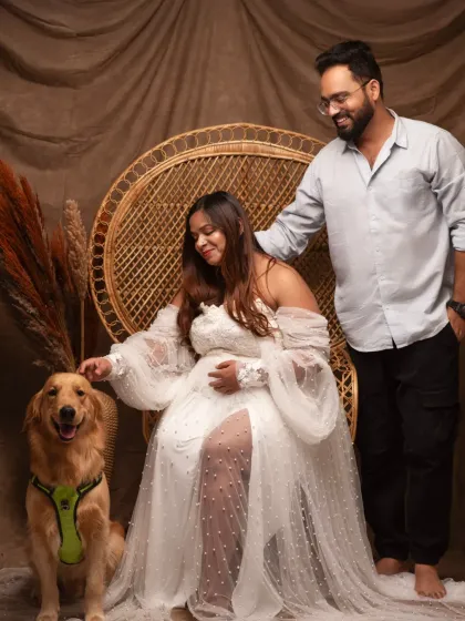 A glamorous maternity shoot with a beautiful flowing gown and a peacock chair. The family dog joins in, making this a portrait of the whole family.