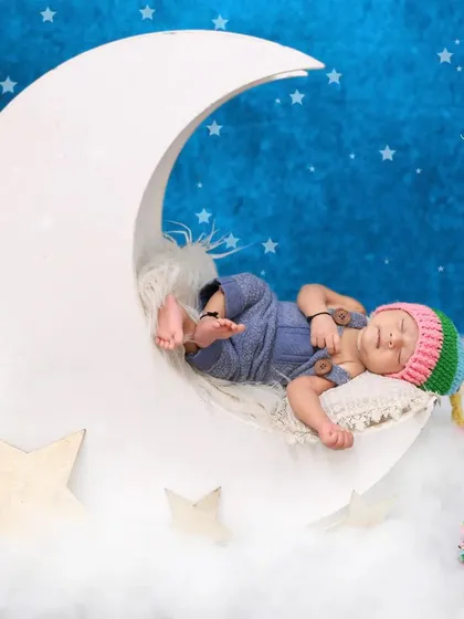 We can customize any theme with adorable accessories. Here, we added a colorful, handmade knit hat to the moon setup, adding a playful and personal touch to this dreamy newborn portrait.