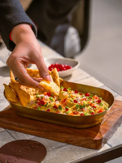 A lifestyle shot capturing the action of dipping a nacho into the modern chaat at Camo.