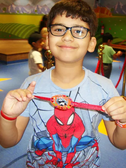 A boy shows off the cool Spider-Man rakhi he made. My Rakhi-making workshops let kids create personalized rakhis for their siblings, adding a special touch to the festival.