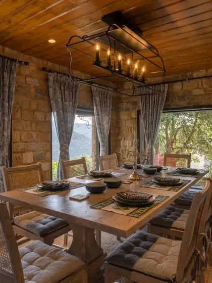 The dining room at Buransh Terraces, where meals are enjoyed with panoramic views of the mountains. The rustic stone walls and warm wood ceiling create a cozy, cabin-like feel.