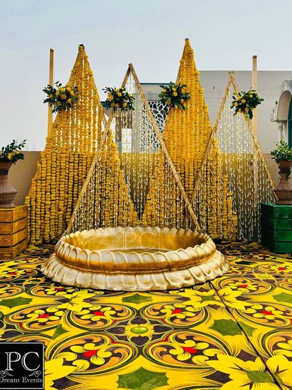 For this rooftop Haldi, I created a unique backdrop with pyramids of 'genda phool' garlands and a large brass urli in the center for the bride to sit in, all set against a vibrant printed carpet.