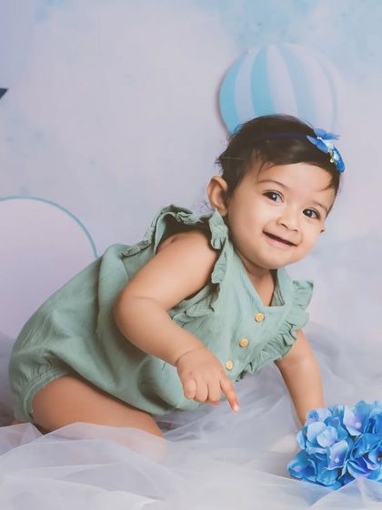 A little girl like a dream. The soft blues and greens in this cloud-themed setup create a beautiful, calming atmosphere for a lovely milestone portrait.