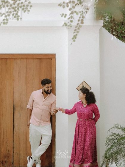 The couple posing by a wooden door, their hands linked, sharing a sweet and gentle moment.